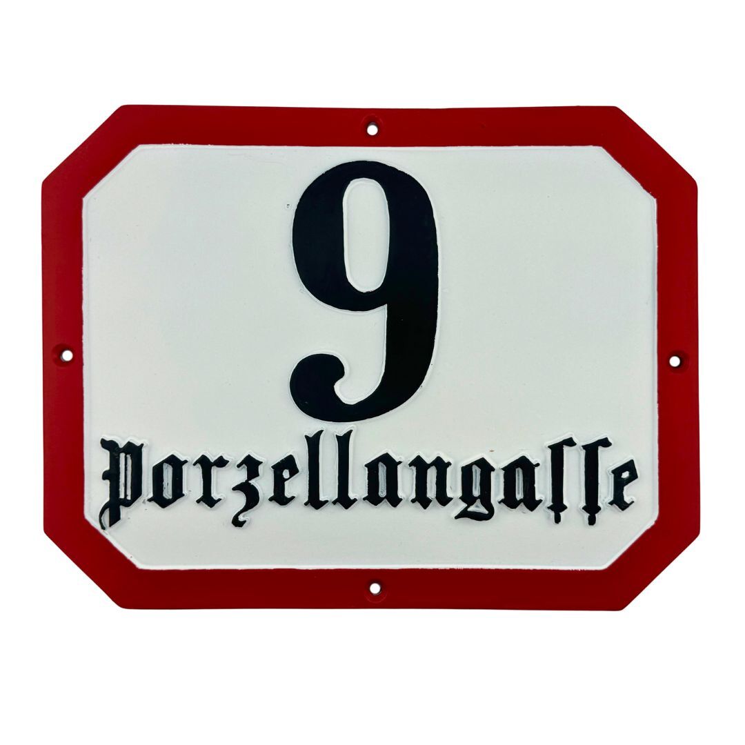 klassisches achteckiges Hausnummernschild aus Aluminiumguss mit roter Umrandung und schwarzer Frakturschrift
