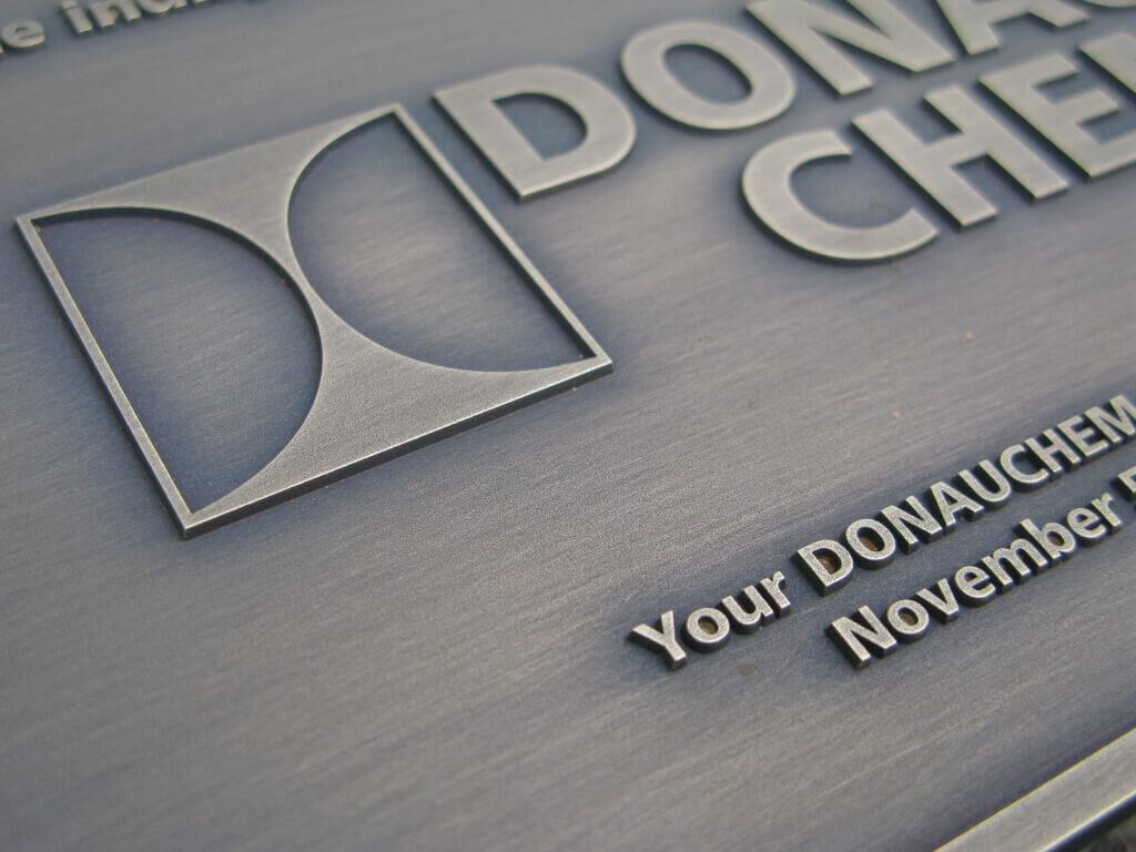 firmenschild-unternehmensschild-messing-patiniert-donauchemie-drab-4 Detailaufnahme vom Firmenschild aus patiniertem Messing