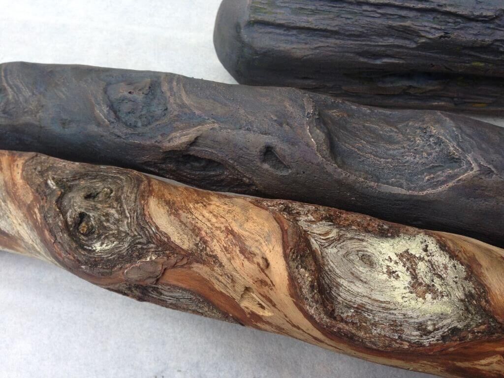 Vorne Baumstamm aus Holz, dahinter Baumstamm aus Bronzeguss Vorne Baumstamm aus Holz, dahinter Baumstamm aus Bronzeguss