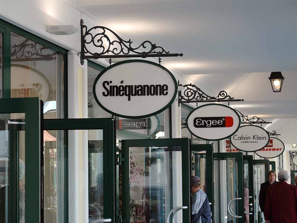 parndorf_designer_outlet_einkaufszentrum_steckschild_ausleger_drab_01 Steckschild bzw. Ladenschild mit Wandausleger aus Metallguss & Schmiedeeisen