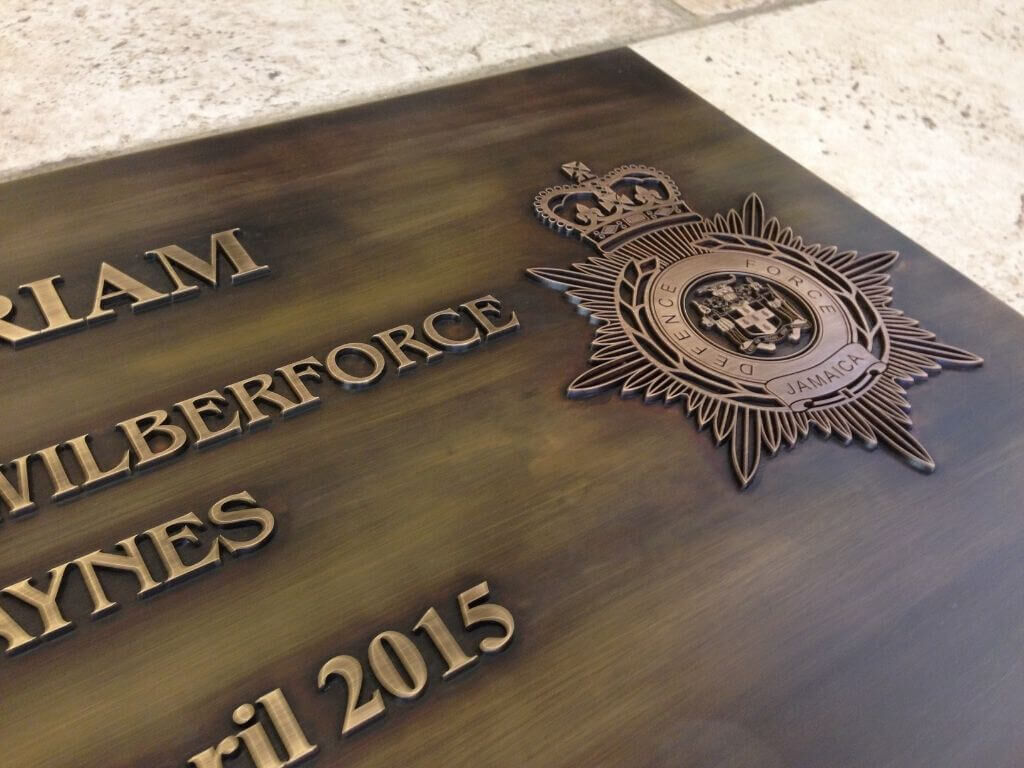 Detailaufnahme des erhabenen Wappen und Schrift der Gedenktafel aus patiniertem Messing Detailaufnahme des erhabenen Wappen und Schrift der Gedenktafel aus patiniertem Messing