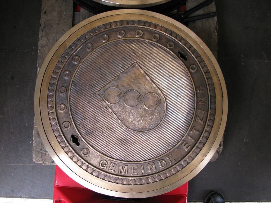 Individulle Schachtabdeckung aus Bronzeguss mit dem Wappen der Gemeinde Eitzing Individulle Schachtabdeckung aus Bronzeguss mit dem Wappen der Gemeinde Eitzing